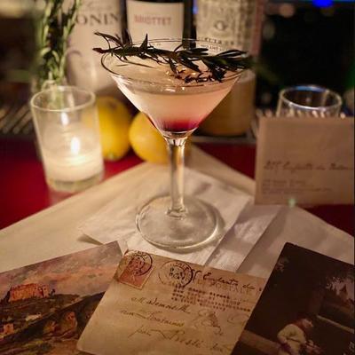 A martini cocktail served on a table with candles and menu.