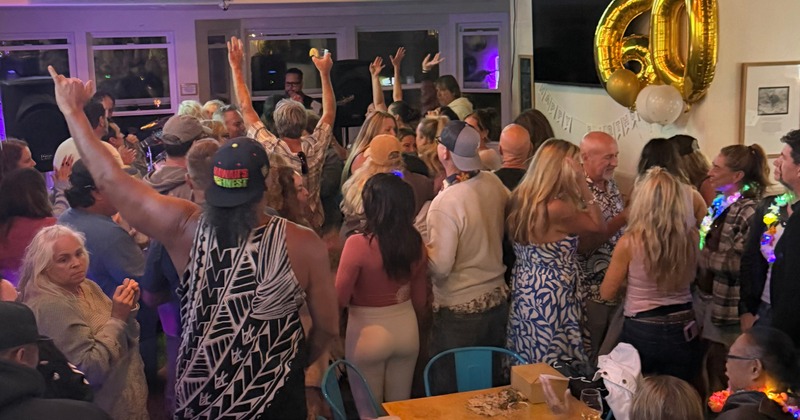 A large group of people celebrating a 60th birthday enjoying dancing to a live band
