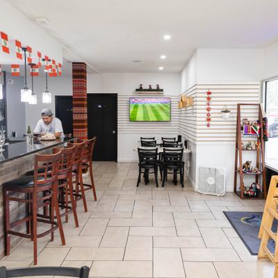 Restaurant interior with bar seating and TV showing sports.