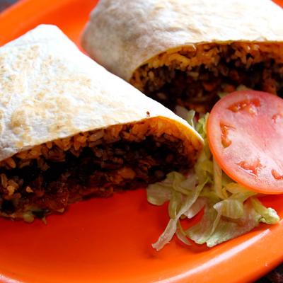 Steak Burrito sliced in half and served with lettuce and tomato slice.