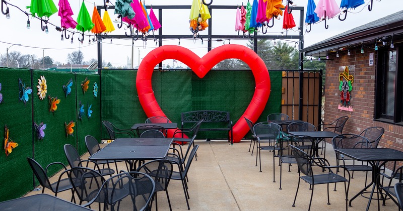 Patio with tables and chairs, colorful umbrellas as decoration above the patio