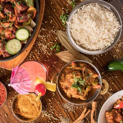 Assorted Indian dishes on a wooden table, with spices scattered around.
