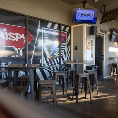 Interior featuring high stools, tables, beer advertisements, and TVs.