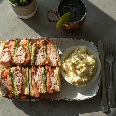 Turkey club served with potato salad and a cocktail.