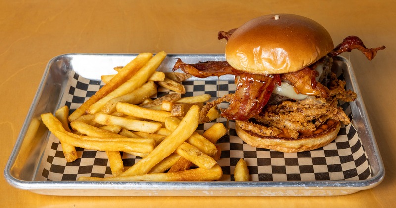 Bacon bourbon burger with onion rings and french fries on a tray