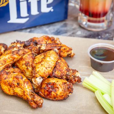 Smoked wings served with celery sticks and a side of sauce.