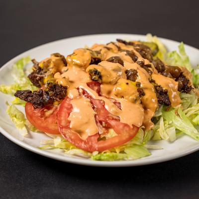 Huda Burger Bowl with lettuce, tomatoes and a drizzle of sauce.