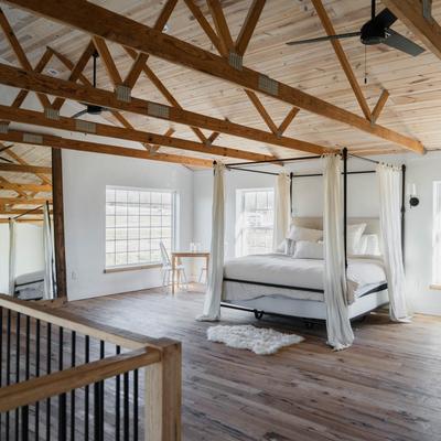 The bedroom with a large bed and wooden beams above.