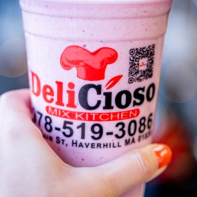 Hand holding a cup with Strawberry Smoothie.