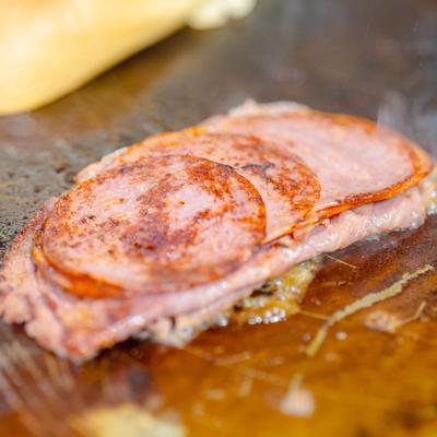 Slices of seared pork ham cooking on a hot griddle, close-up.