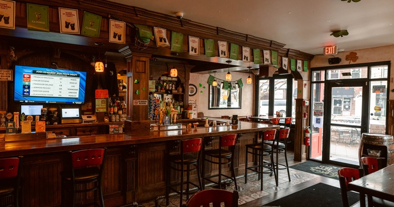 Interior of a pub with a bar, stools and St. Patrick's Day decorations.