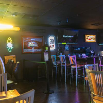Interior of a bar with neon signs, bar stools and flat-screen TVs..