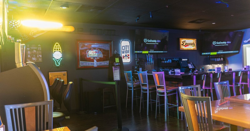Interior of a bar with neon signs, bar stools and flat-screen TVs.