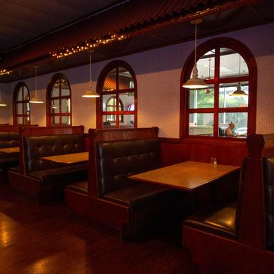 Interior featuring dark wood booths, hanging lamps, and arched windows.