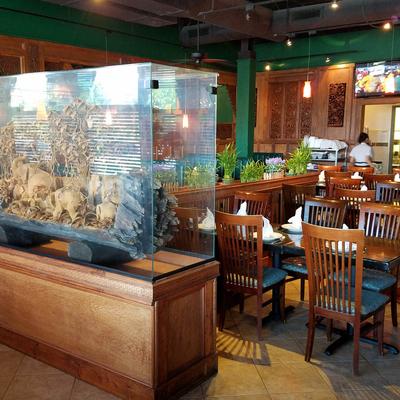 Dining area, tree log carving in a glass case, tables with tableware, wall TV.