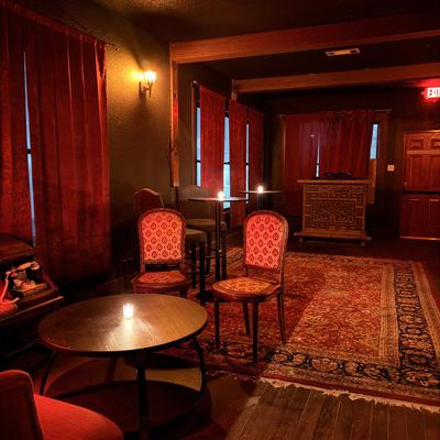 Dim lounge with red curtains, small table, and chairs.