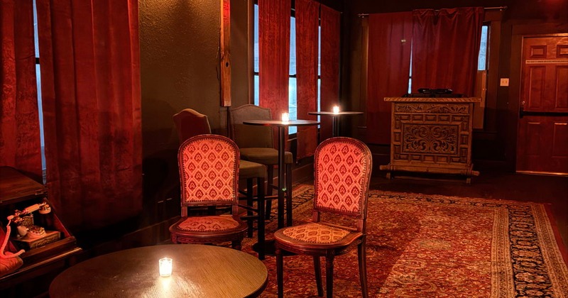 Dim lounge with red curtains, small table, and chairs