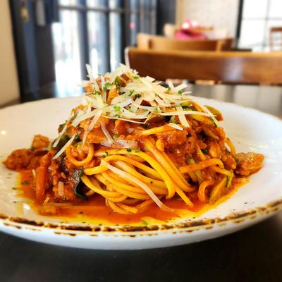 A plate of spaghetti topped with meat sauce and shredded cheese.