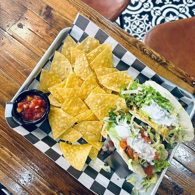 A meal featuring tacos and tortilla chips with salsa.
