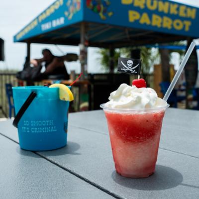 Frozen strawberry drink topped with whipped cream and a cherry served outdoors.