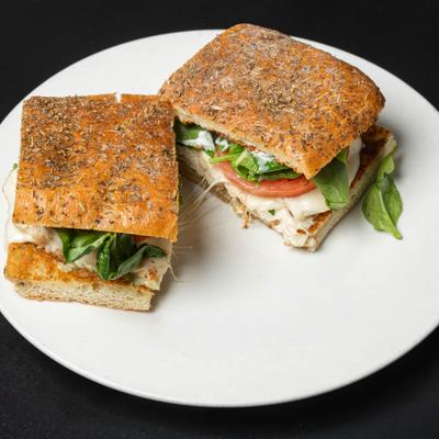 Chicken Pesto Sandwich sliced in half and served on a white plate.