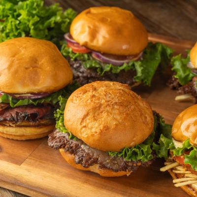 Variety of gourmet cheeseburgers served on a wooden platter.