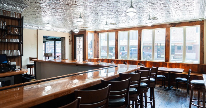 Interior, bar and seating area, wooden top bar with stools, banquette seating in the back