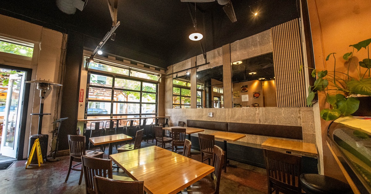 Modern interior with wooden tables, dark chairs, large windows and ceiling fans
