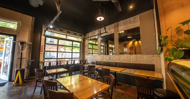 Modern interior with wooden tables, dark chairs, large windows and ceiling fans