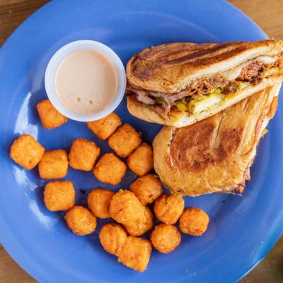 Cuban sandwich with tater tots and a sauce.