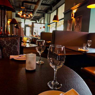 Dinner table set with wine glasses and plates, brown booths in the background.