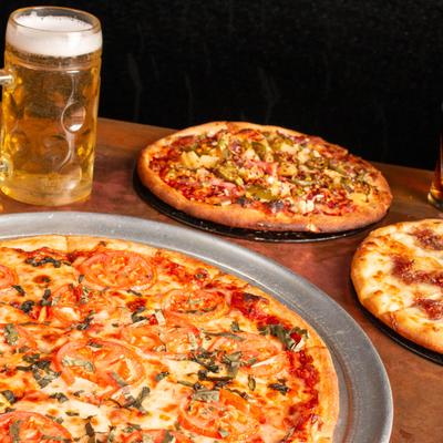 Three pizzas and a beer on a table.