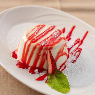 Panna cotta dessert drizzled with a vibrant berry coulis.