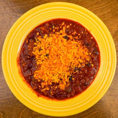 Bowl of chili topped with shredded cheese.