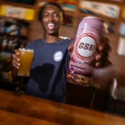 person holding glass of beer and can of beer.