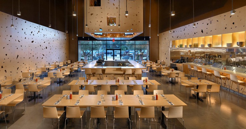 Interior, wide shot of the restaurant, bar at center, dining tables around, entrance in the back