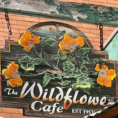 The restaurant sign outside on a hanging wooden board.