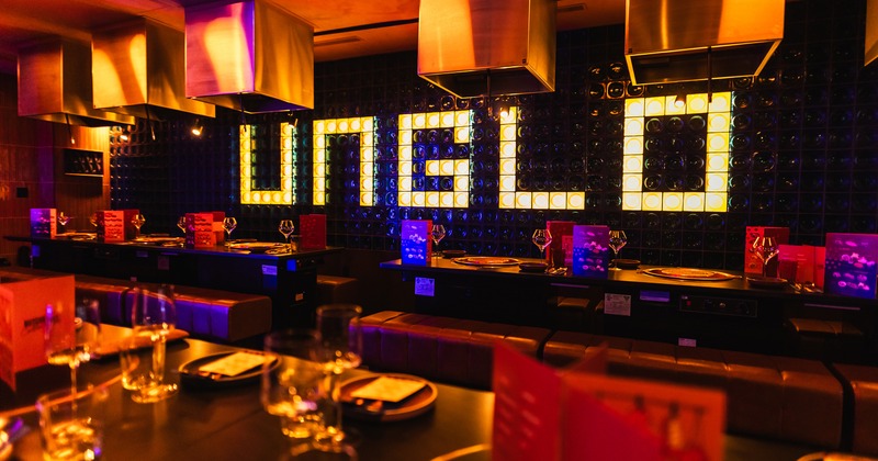 Interior of a modern dining area with set tables, a restaurant logo on the wall