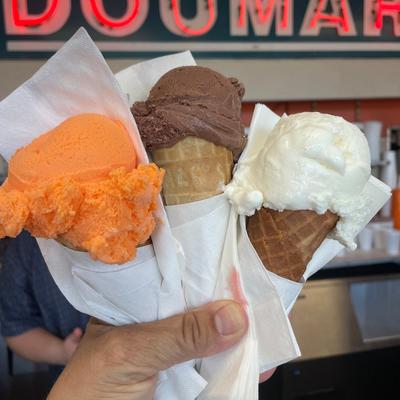 single dip cones of orange sherbet, chocolate, and vanilla ice cream.