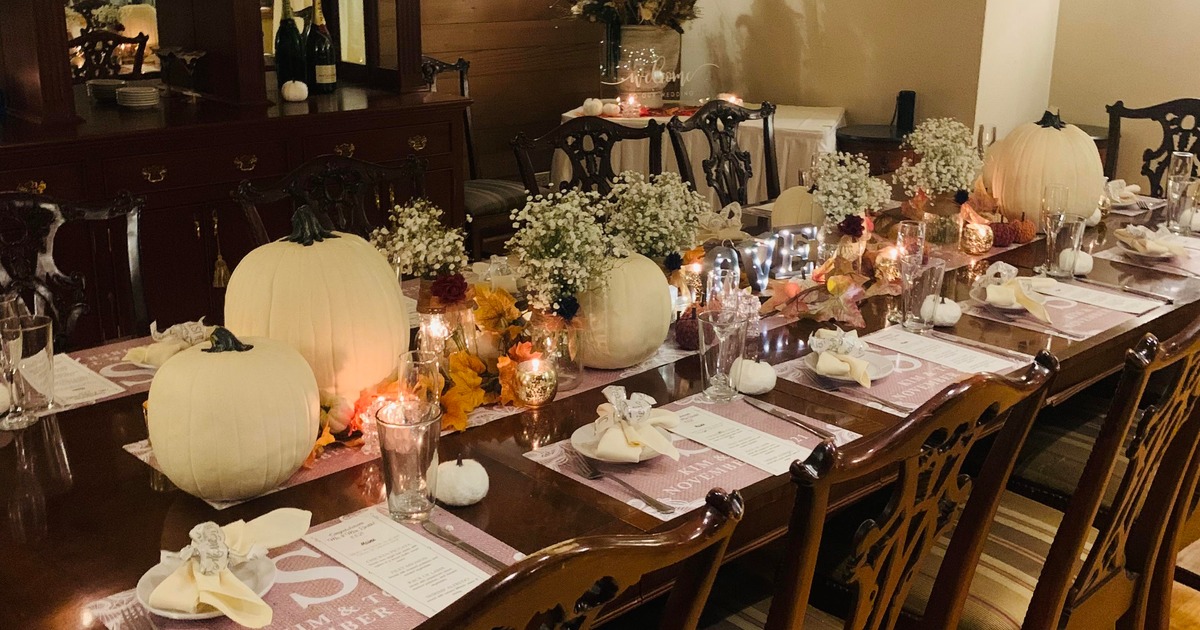 Cellar room dining table, fully set, decorated with flowers, candles, and pumpkins