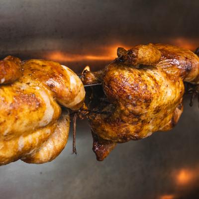 Whole chickens roasting on a rotating spit.