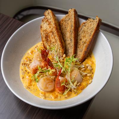 Creamy seafood dish with shrimp, scallops, toasted bread slices, and pine nuts.