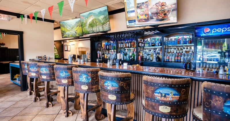 Bar, bar stools, drink rack behind, tv screens above