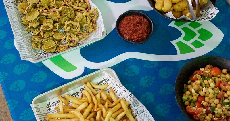Fried pickles, French fries, chickpea salad, and dipping sauce spread on a table