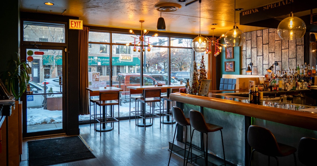 A modern interior with a bar area, seating by windows and decorative lighting