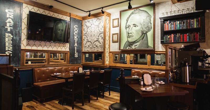 Seating area with TV, bookshelves on a wall and a portrait of founding father Alexander Hamilton