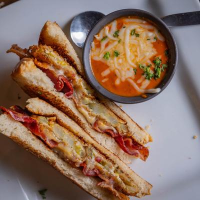 Grilled cheese sandwich with bacon and fried green tomato, accompanied by tomato bisque.