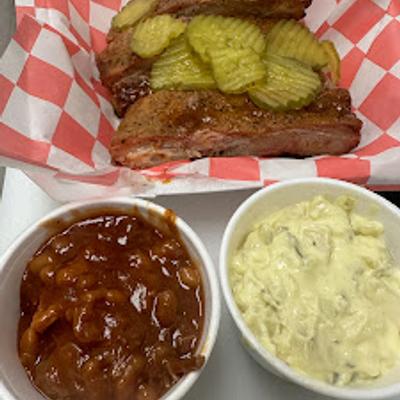 Ribs topped with pickle and served with beans and potato salad.