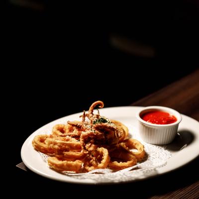 Plate of fried calamari served with a side of marinara dipping sauce.