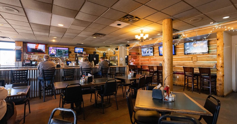 Interior, tables and chairs ready for guests, tv screens on the wall